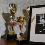 A collection of trophies with a framed black and white portrait on a shelf.